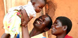 Photo of a father holding up his baby with the mother looking on.