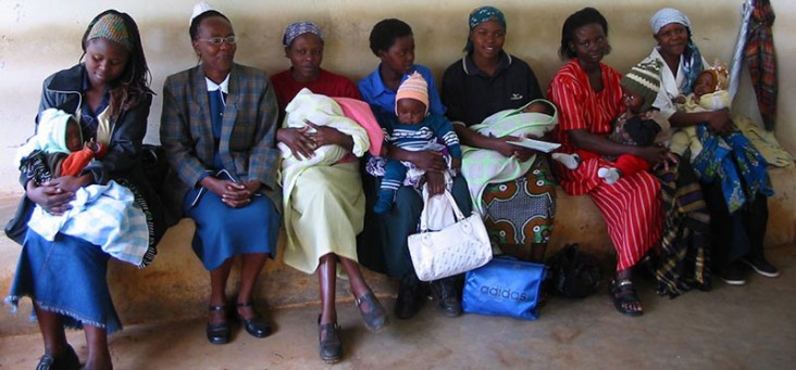 Women with their babies sit on a bench