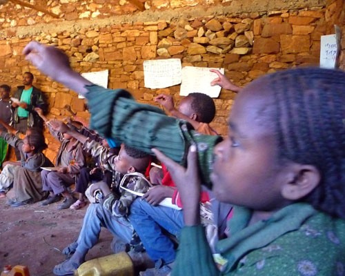 Third graders raise their hands at a USAID-sponsored Alternative Basic Education Center providing accessible schooling for young