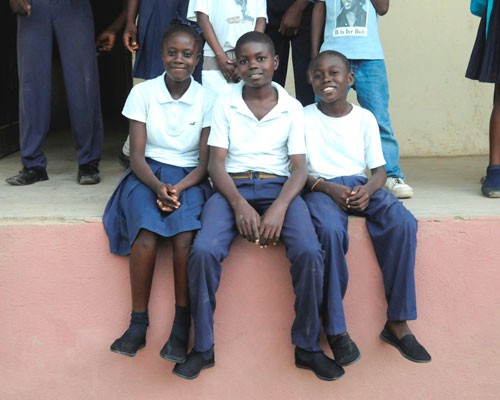 Johnie Pierre, center, sits on a porch at the Ecole Nationale de l'Acul du Nord with his sister Sherline and his brother Wendi a