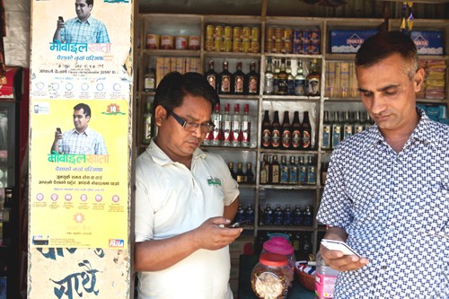 Krishna Prasad Bhattarai, right, uses his cell phone to transfer money to his daughter’s account for payment of her school fees.