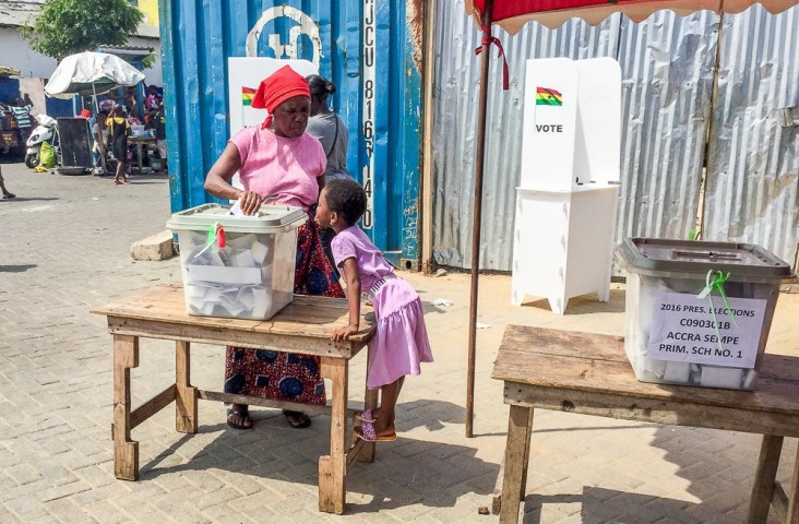 A child watches as her mother puts her ballot in the secured ballot box.