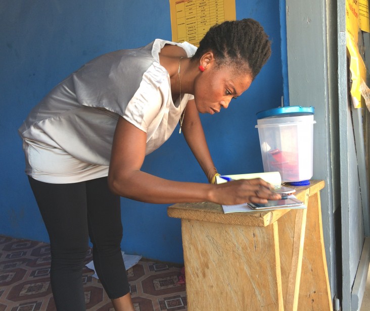 Sylvia records mobile money transactions in a paper ledger.