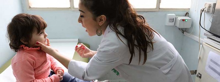 A medical technician checks on a young girl.