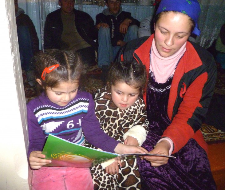 Amida Taqieva reads to her daughter Elvira, far left, and a friend in Deh, Tajikistan.