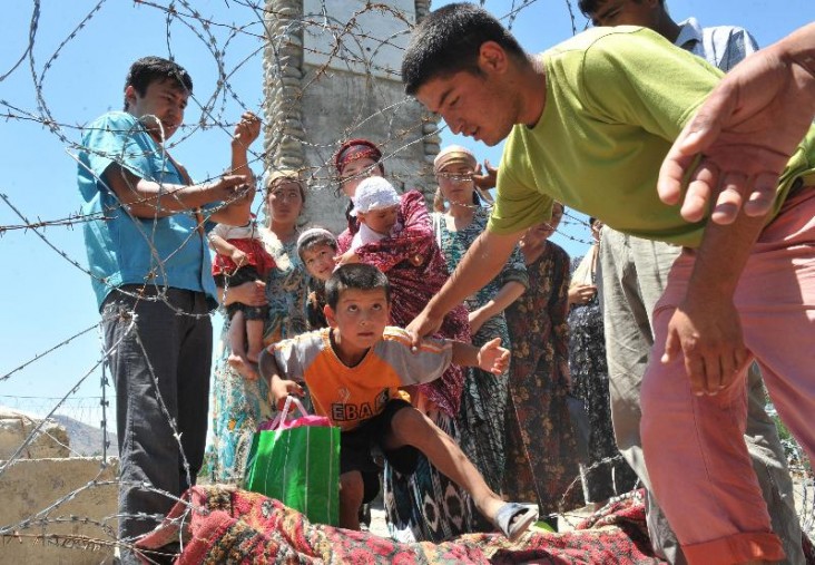 Ethnic Uzbek refugees cross the Kyrgyz-Uzbek border on their way back to Kyrgyzstan near the village of Vlksm some 20 km outside