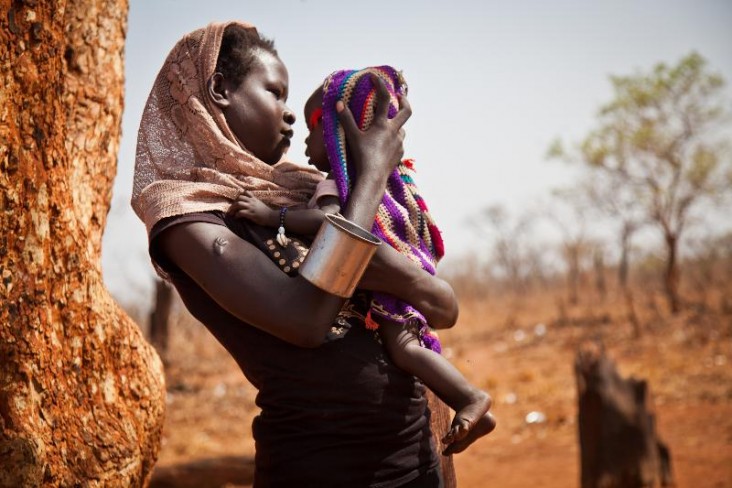 A woman and her child from the Nuba Mountains in Sudan wait outside of the Yida refugee camp registration center in South Sudan