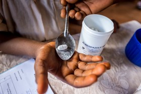 A hand holding pills and a cup