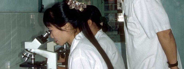 A technician looks through a microscope