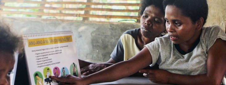 A woman points to a flip chart about tuberculosis