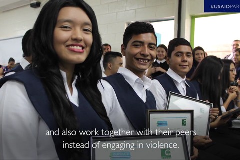 Students holding framed certificates while smiling