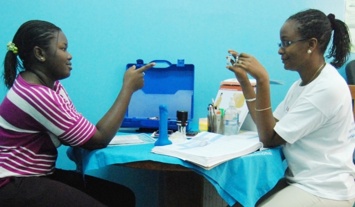 A family planning counselor displays oral contraceptives to a university student