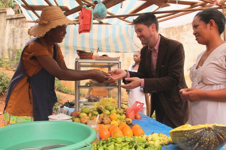 Christopher La Fargue, a USAID Food For Peace officer, buys fruit at Honorine’s food stand