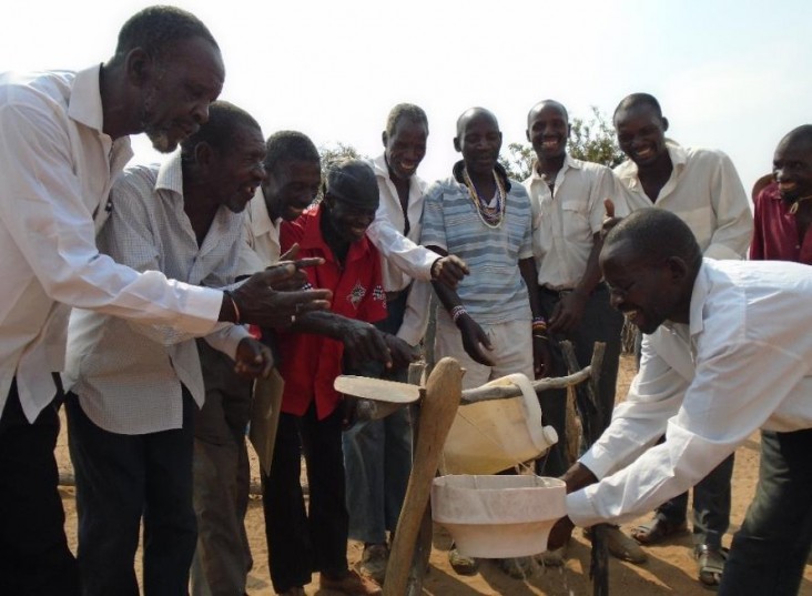 The men of the Asisizaneni Community Health Club demonstrate how to use a tippy tap for hand washing.