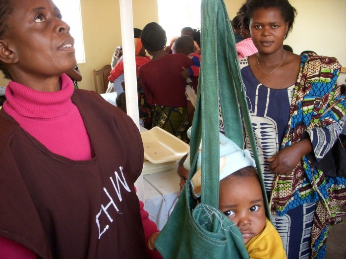 During Child Health Week in Zambia, community health volunteer Mary Kafumbe weighs Joshua Matabula under the watchful eye of his