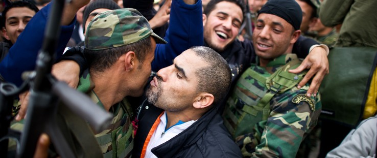 Tunisian protesters kiss soldiers during a demonstration against the presence of the toppled ruling party in the transitional go