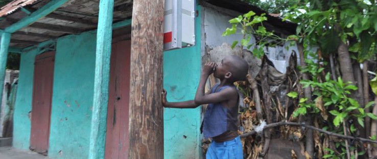 A Haitian boy inspects the installation of an early-stage microgrid meter box.