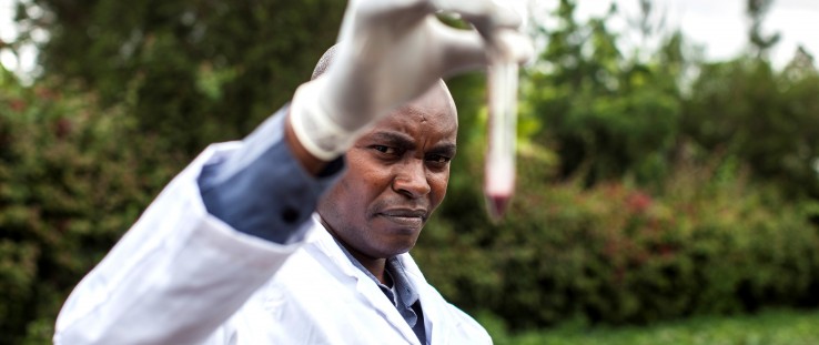 An agricultural extension worker inspects the color of a pH soil test.