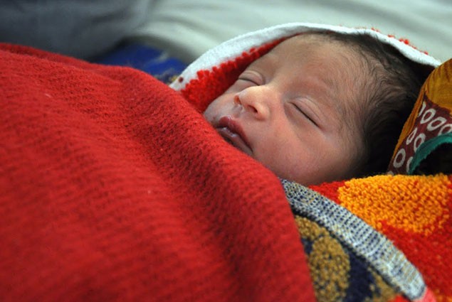 A newborn baby is swaddled in blankets