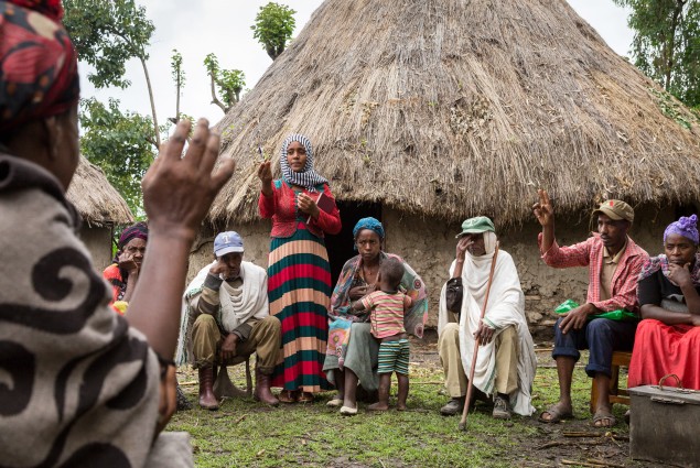 A member of Nigat Chora (Sunrise) Village Economic and Social Association (VESA) raises her hand to speak and is called on by Community Facilitator Zemsem Kefir during a VESA meeting. Comprised of groups  of neighbors and peers, VESAs are the foundation of all USAID-supported activities. VESAs also provide savings and credit facilities to members. When Nigat Chora was established five years ago, its 23 member households were some of the poorest in the community. Today a 'culture of saving' has helped transf