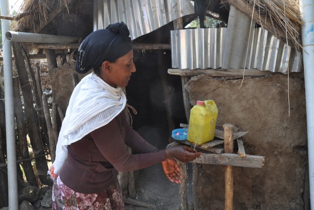 Belaynash, a model family trained by the village health extension worker, demonstrates their family tippy tap in Wara Village.