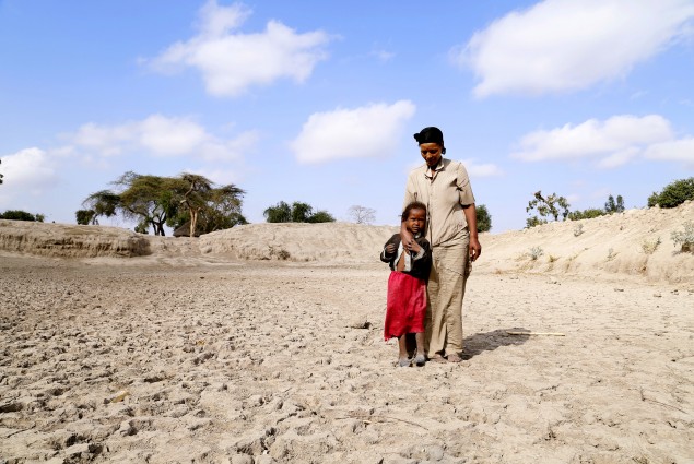 Badoo Fukura and one of her daughters stand at the bottom of a basin that used to be their community watering hole. 