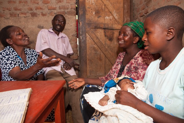 A teen mom sits with community workers and her family.