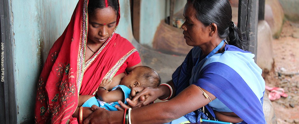 A health worker helps a new mother nurse her baby.