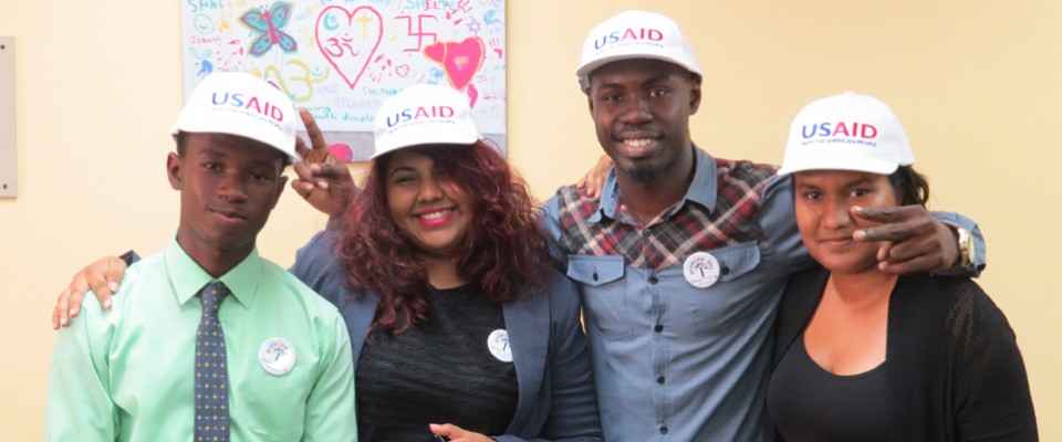 President and members of Guyana's National Youth Council celebrate with one of the social cohesion community murals featured in the background.