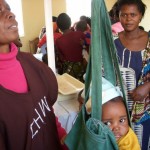 During Child Health Week in Zambia, community health volunteer Mary Kafumbe weighs Joshua Matabula under the watchful eye of his