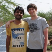 Yashraj Khaitan (left) and Jacob Dickinson, both founders of Gram Power, stand next to several solar panels in India. The panels