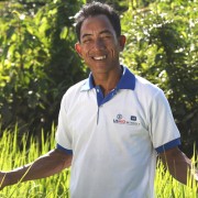 Kverk Sarak stands in his family’s rice field on community titled land. 