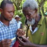 The man on the left explains how to use mobile money in Haiti's Pandiassou community as part of a USAID grant to Mercy Corps.