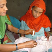 A community health volunteer applies chlorhexidine to the umbilical cord of a newborn delivered at home in Banke district.