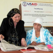 Rural Women Legal Aid Center Director Mukarrama Egamnazarova, left, discusses an article in the USAID Land Reform Project's news